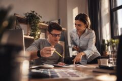Man en vrouw bespreken samen ontwerpen en kleurstalen aan een bureau.